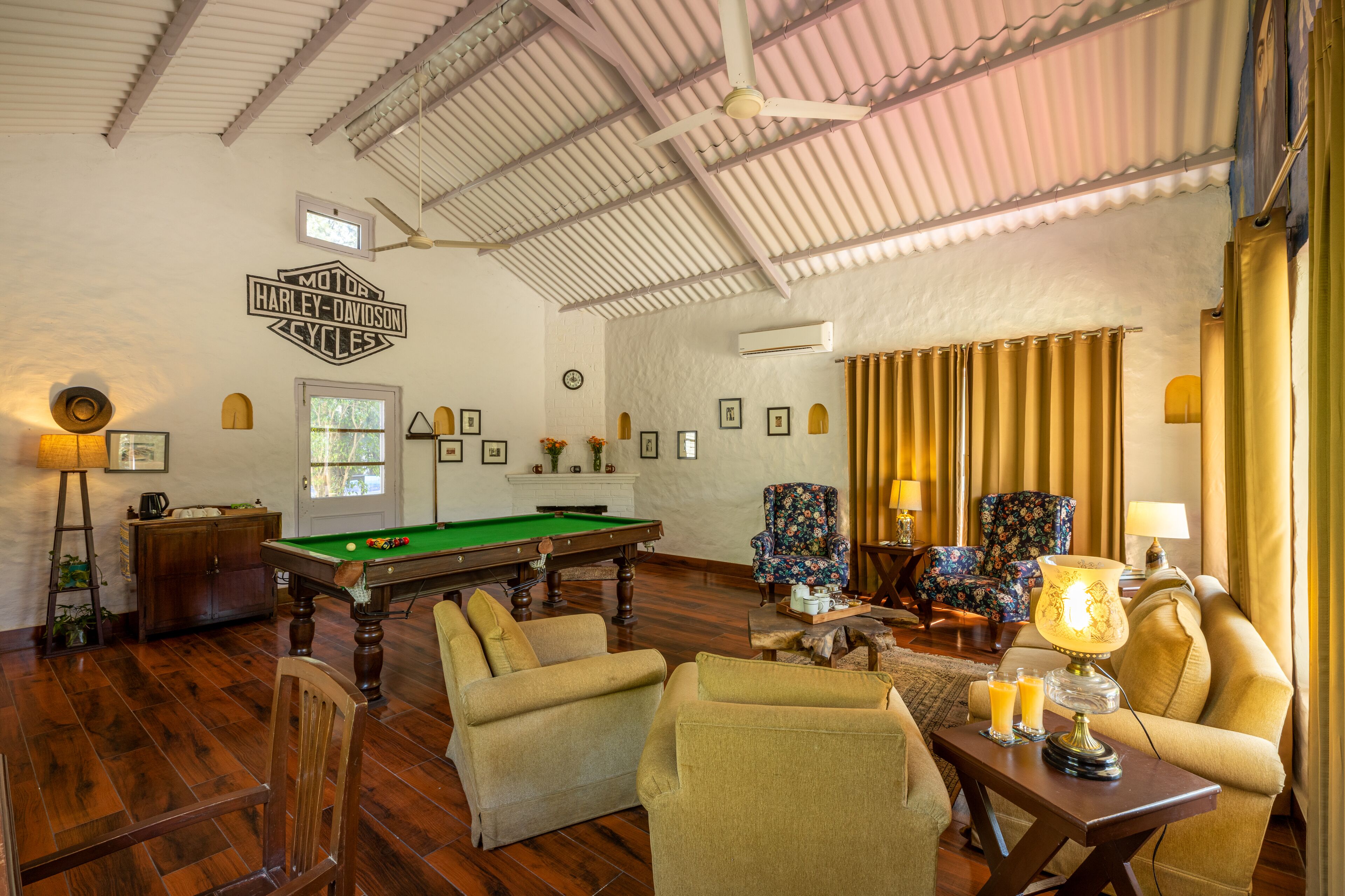 Um quarto espaçoso com mesa de bilhar, assentos confortáveis e um ventilador de teto.