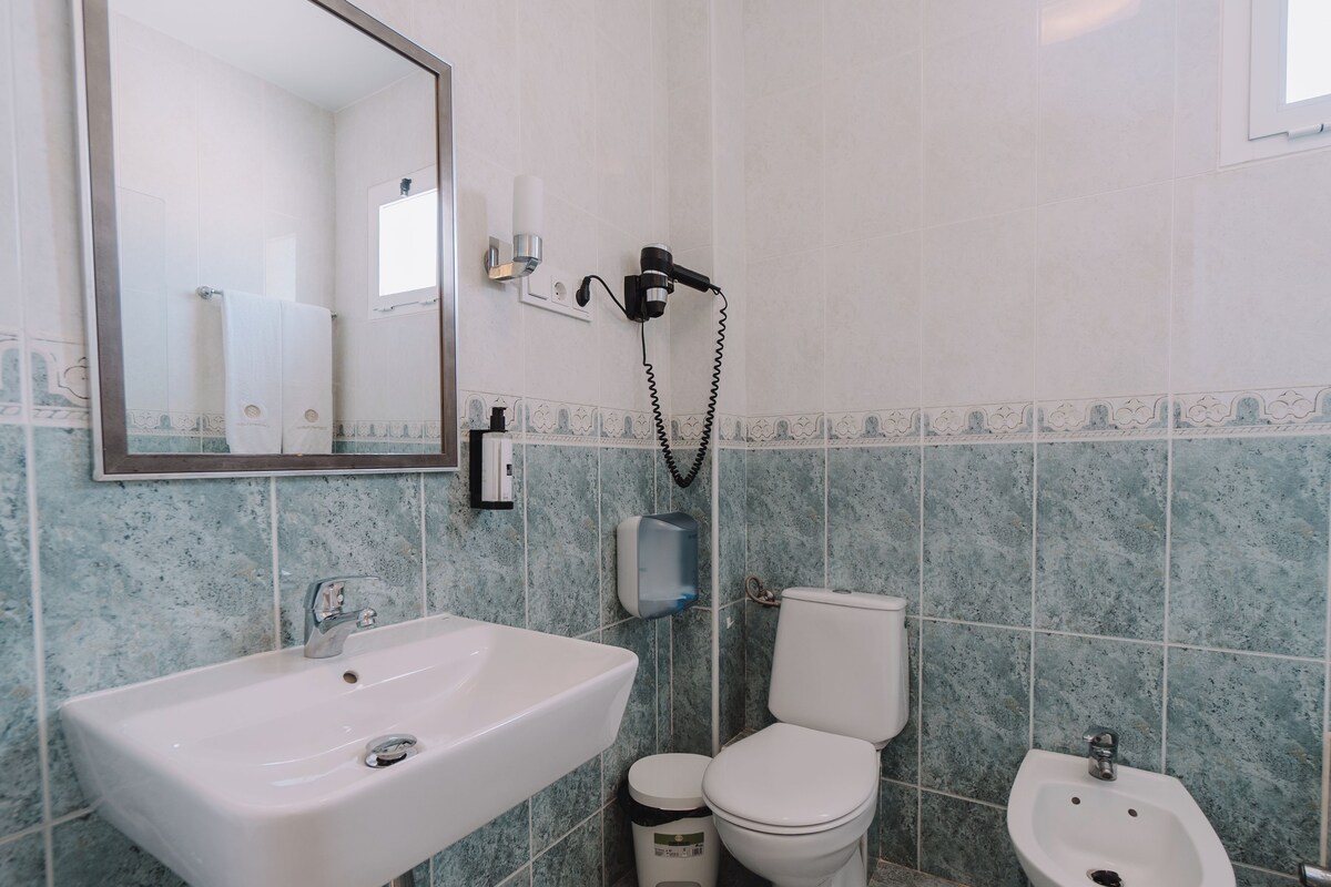 Un baño con lavamanos, inodoro, bidé y espejo.