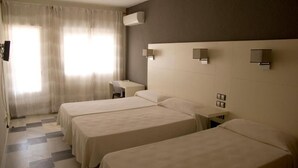 A hotel room with three beds, a desk, and a chair. - Hostal Las Gaviotas del Cabo (Nijar)