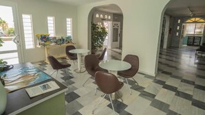 A spacious lobby with a checkered floor, a reception desk, and several seating areas with chairs and tables. - Hostal Las Gaviotas del Cabo (Nijar)