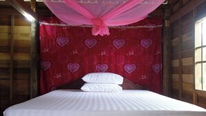 Una cama con dosel, un pared con estampado rojo y paredes de madera.