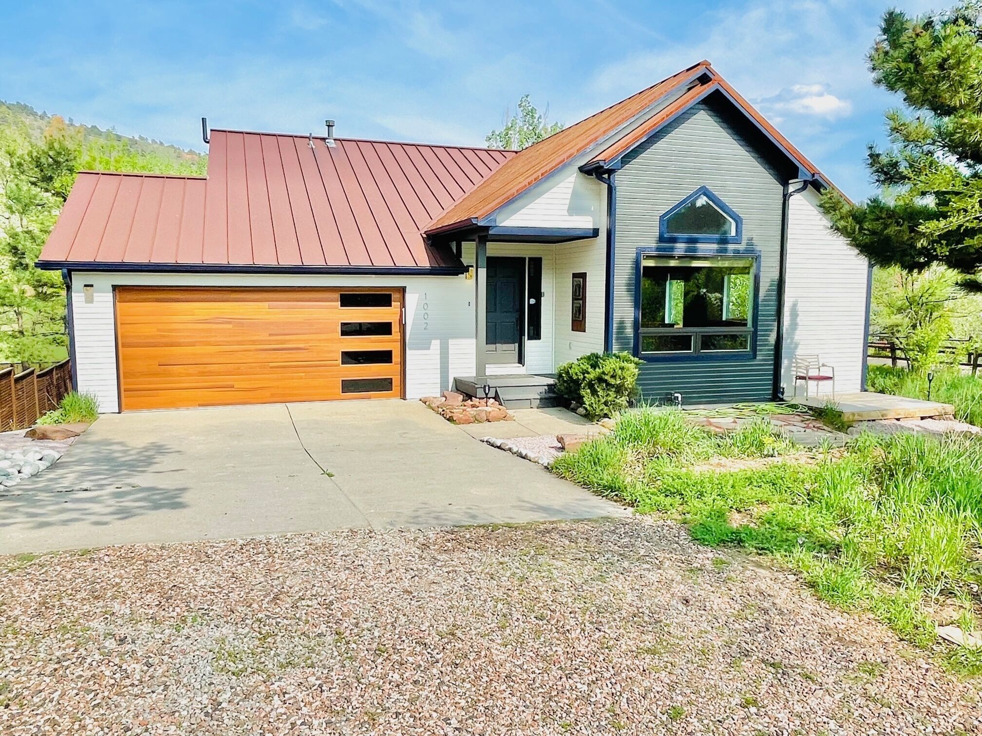 Une maison à deux étages avec un garage, un porche à l’avant et un petit jardin.