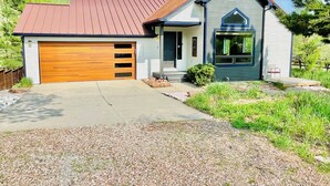 A two-story house with a garage, a front porch, and a small garden area. - Walkout Basement 
from a Superhost! (Lyons)