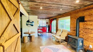 A rustic interior with a wooden ceiling, a stone fireplace, and a dining area with a round table and chairs. - Walkout Basement 
from a Superhost! (Lyons)