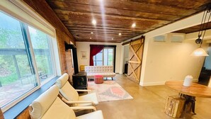 A spacious living area with a large window, a fireplace, and a dining table. - Walkout Basement 
from a Superhost! (Lyons)