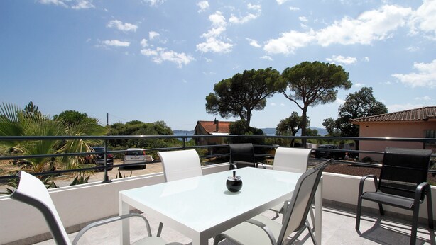 An outdoor patio with a table and chairs, overlooking a scenic view with trees and a distant building. - Apartment 60 M2 with 2 Bedrooms and 2 shower rooms Sea View 300 M from the sea (Sainte-Maxime)