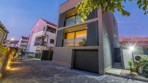 Un moderno edificio residencial de varios pisos, con garaje, balcón y vistas a las montañas.