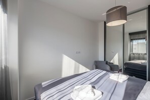 Ein modernes Hotelzimmer mit einem Bett, einem Sessel, einem Schreibtisch und einem großen Spiegel.