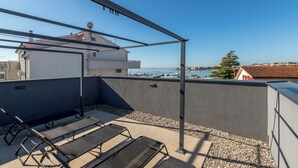 Una terraza en la azotea con vista al mar, una pérgola y dos sillones de descanso.