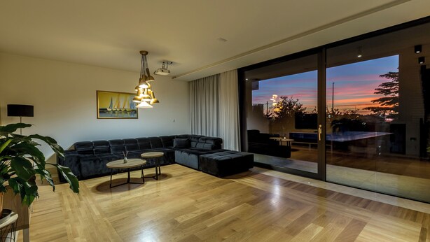 Una sala de estar moderna con un sofá modular, una mesa de centro redonda y un amplio ventanal que da a un espacio exterior.