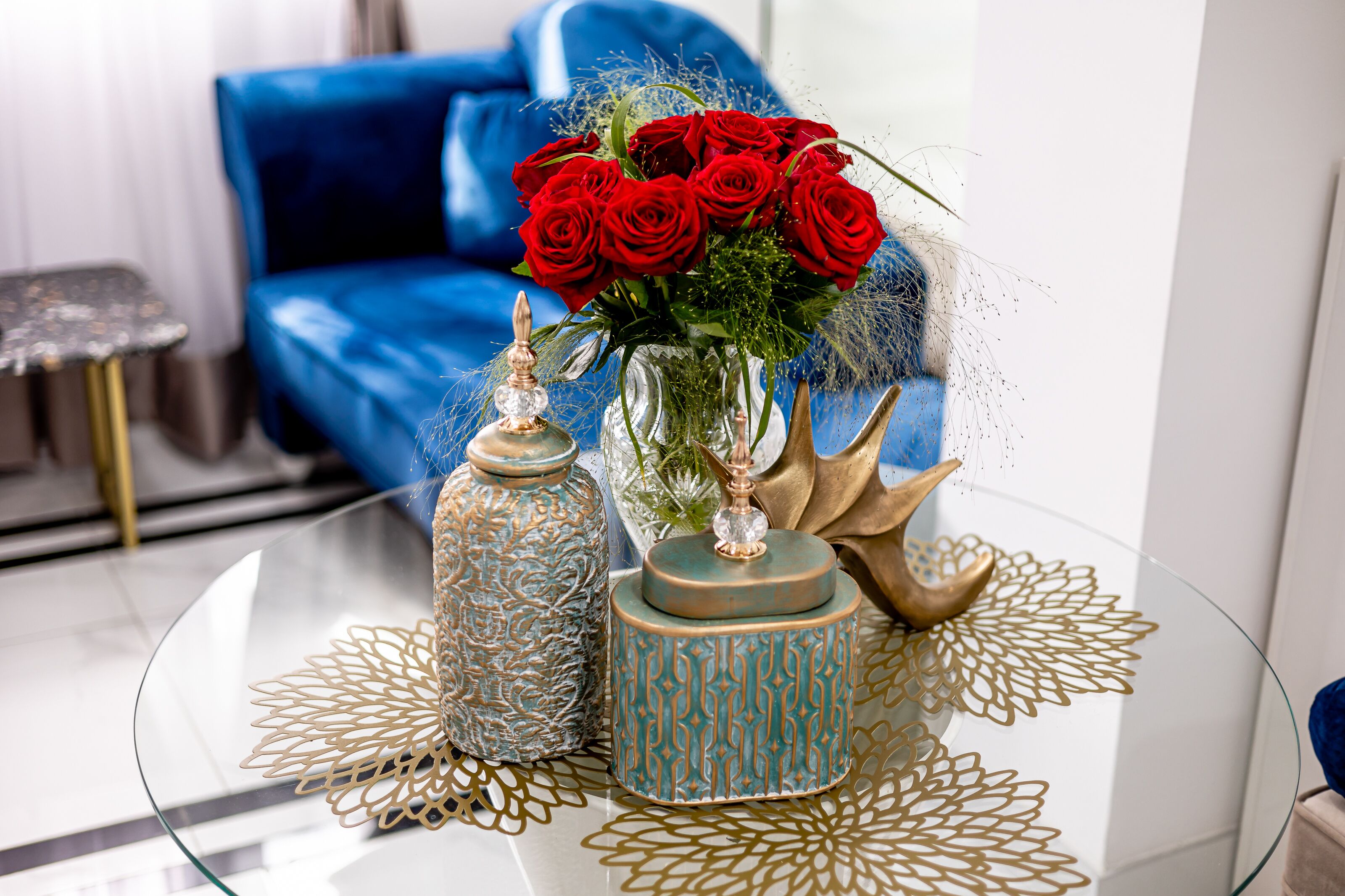 A glass table with decorative vases and a bouquet of red roses.