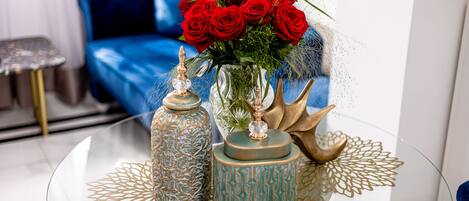 Une table en verre ornée de vases décoratifs et d’un bouquet de roses rouges.