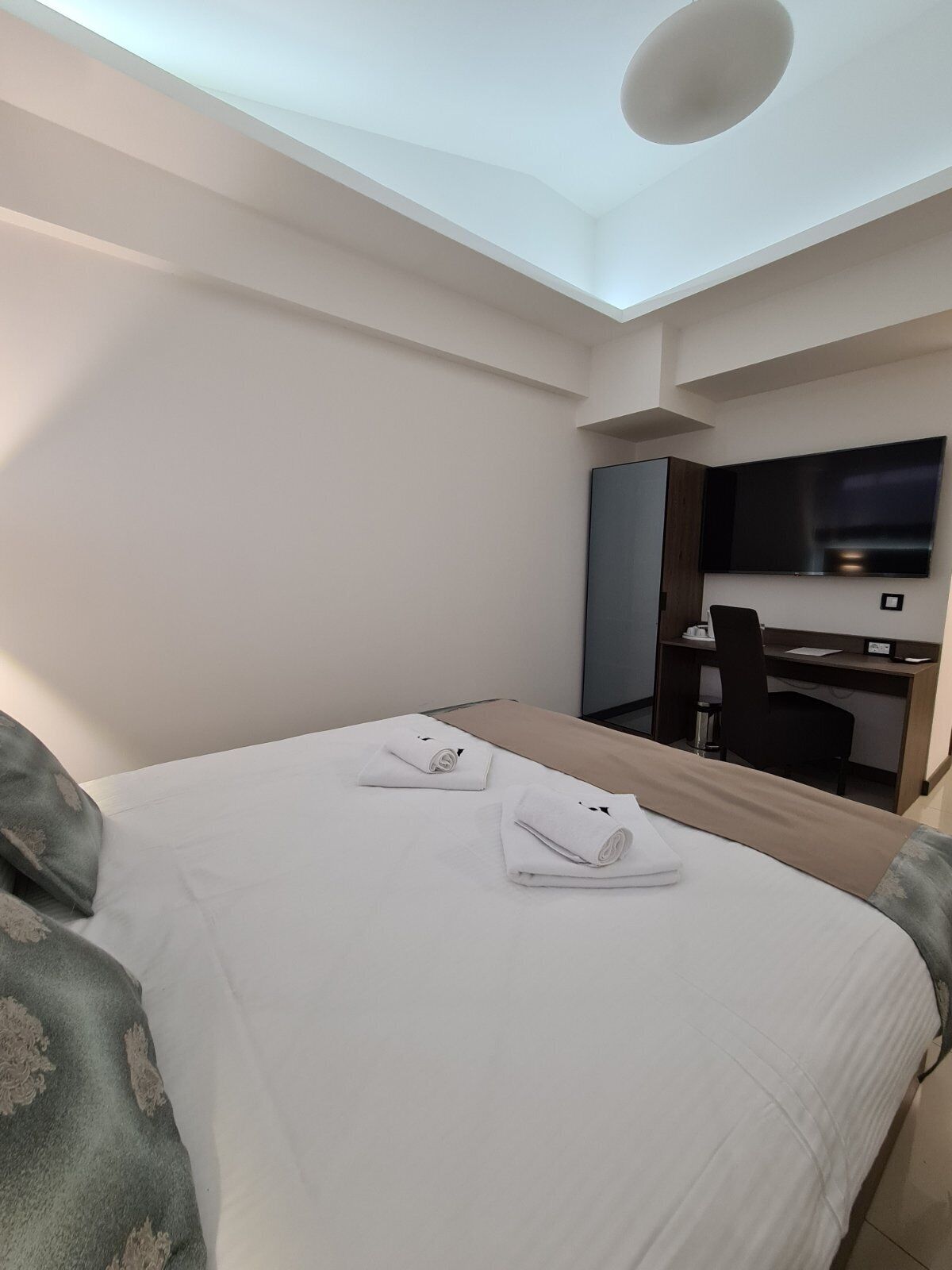 Una habitación de hotel con cama, escritorio, silla y televisor.