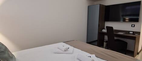 Una habitación de hotel con cama, escritorio, silla y televisor.