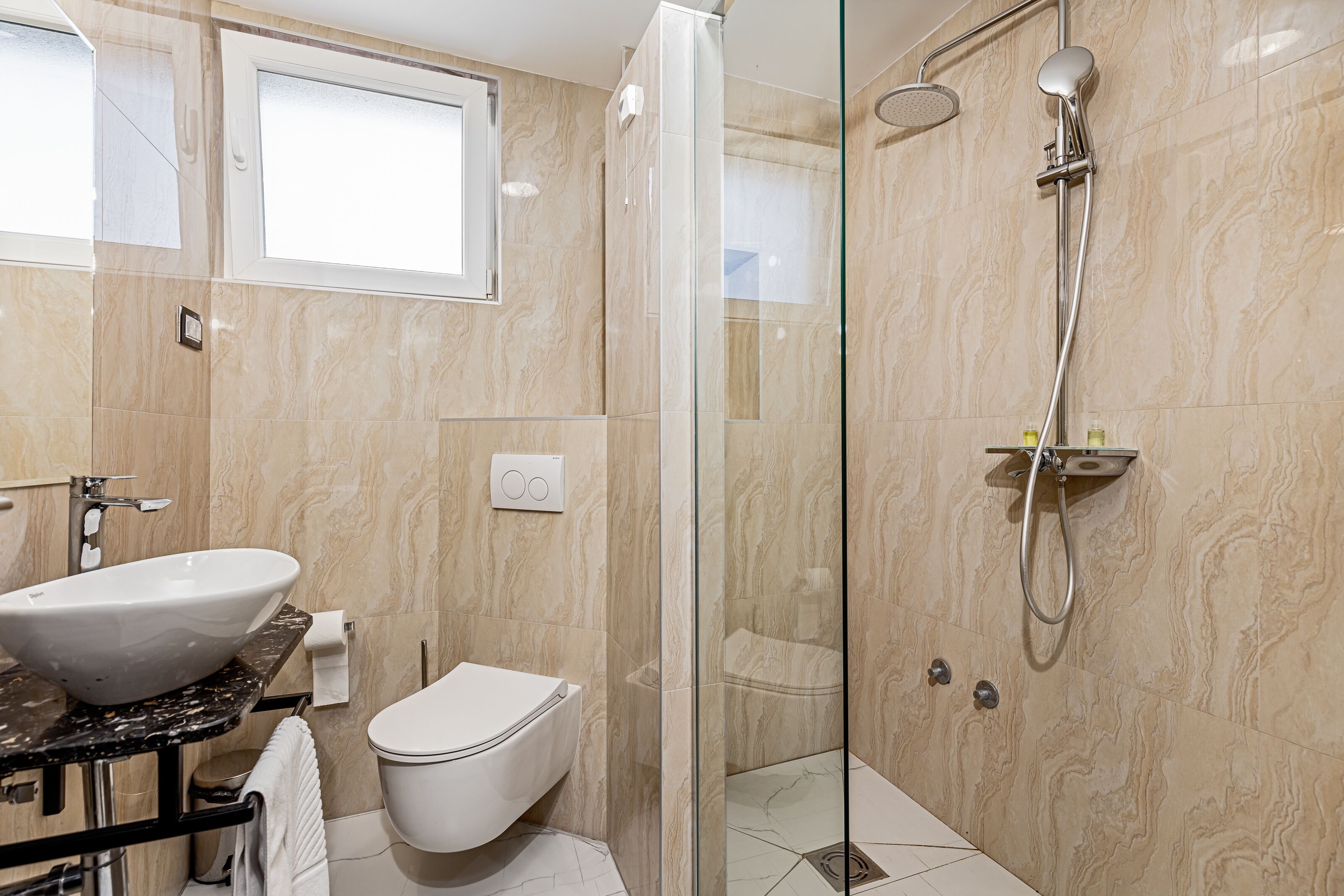 A bathroom with a glass-enclosed shower, a white sink, and a toilet.