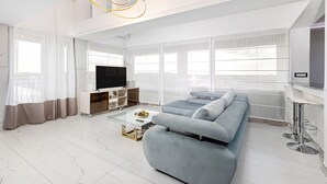 Una sala de estar moderna con un sofá modular, una mesa de centro de vidrio y un televisor.