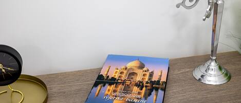 A book titled "UNESCO-ove syetiske bastine" on a wooden surface, a black clock, and a silver candelabra.