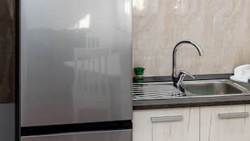 Una cocina con refrigerador de acero inoxidable, un lavamanos y armarios de tonos claros.