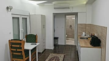 A compact kitchen with a dining area, a built-in oven, and a shower visible through a glass door.