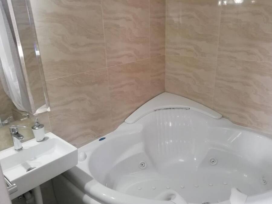 Baño con una bañera blanca, un lavabo y un espejo.
