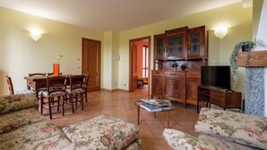 Una sala de estar con comedor, armarios de madera, televisor y sofás estampados con motivos florales.