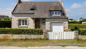 A two-story house with a stone facade, a gabled roof, and a white garage door. - Ar Wellen by Interhome (Cléder)