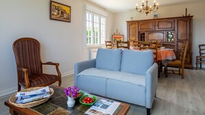 A living room with a sofa, a dining table with chairs, a chandelier, and a window. - Ar Wellen by Interhome (Cléder)