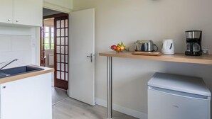 A modern kitchen with a built-in dishwasher, a fruit bowl on the counter, a toaster, a coffee maker, and a clock on the wall. - Ar Wellen by Interhome (Cléder)