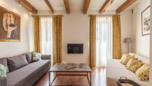 A living room with a sofa, a coffee table, and curtains. - Roof Cathedral Sevilla (Sevilla)