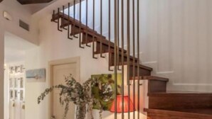 A wooden staircase with a metal railing leading to an upper floor. A light blue cabinet with a glass door is placed at the bottom of the stairs. - Roof Cathedral Sevilla (Sevilla)