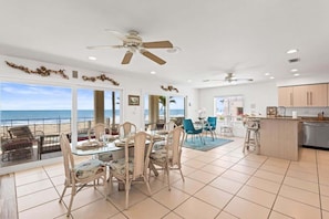 A spacious living area with a dining table, chairs, and a view of the ocean.