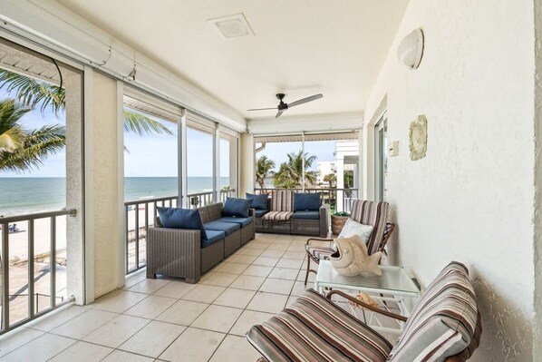 A balcony with a view of the sea, furnished with wicker sofas and striped cushions.