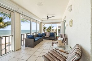 A balcony with a view of the sea, furnished with wicker sofas and striped cushions. - Vista Mar Beachfront Home in Redington Beach (redington beach)