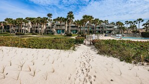 A beachfront hotel with palm trees, a pool, and a sandy walkway. - Aldea 14 Beachfront Townhouse in Belleair Beach (Belleair Beach)