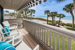 A balcony with wicker chairs and a view of the beach.
