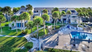 A resort with multiple buildings, a swimming pool, and palm trees. - Aldea 14 Beachfront Townhouse in Belleair Beach (Belleair Beach)