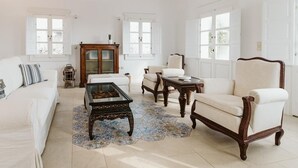 Un ampli saló amb un sofà blanc, una taula de centre de fusta i un butac armchair color crem.