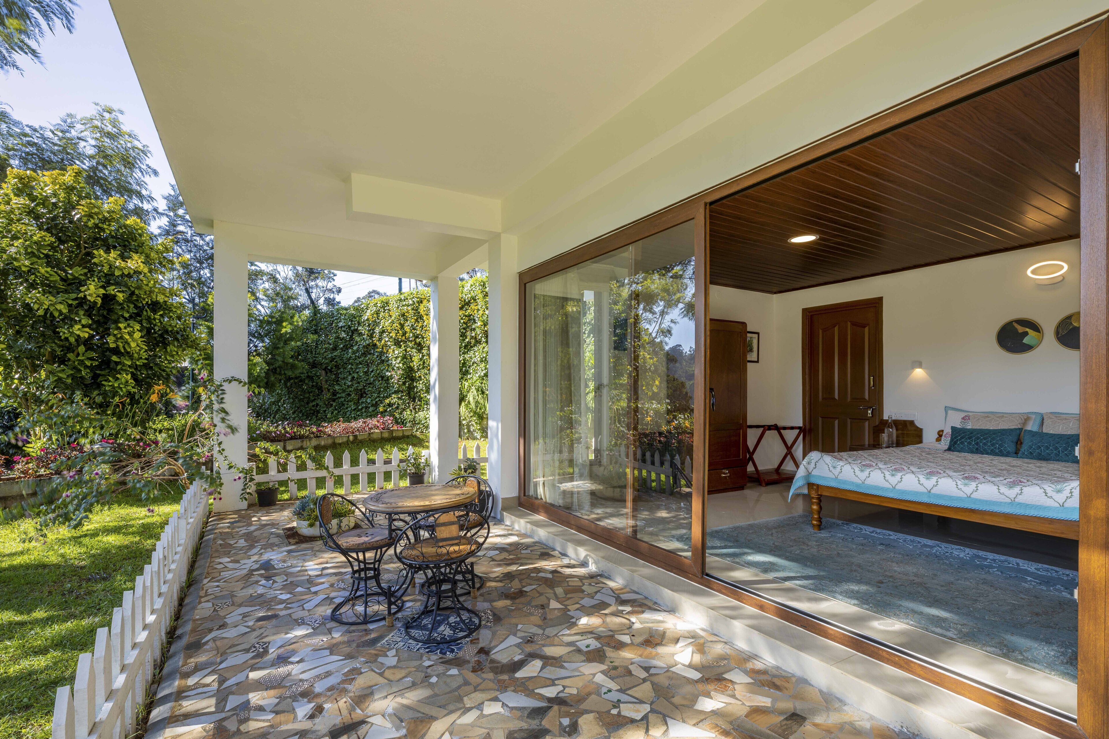 A bedroom with a large sliding glass door leading to a patio area with a dining table and chairs.