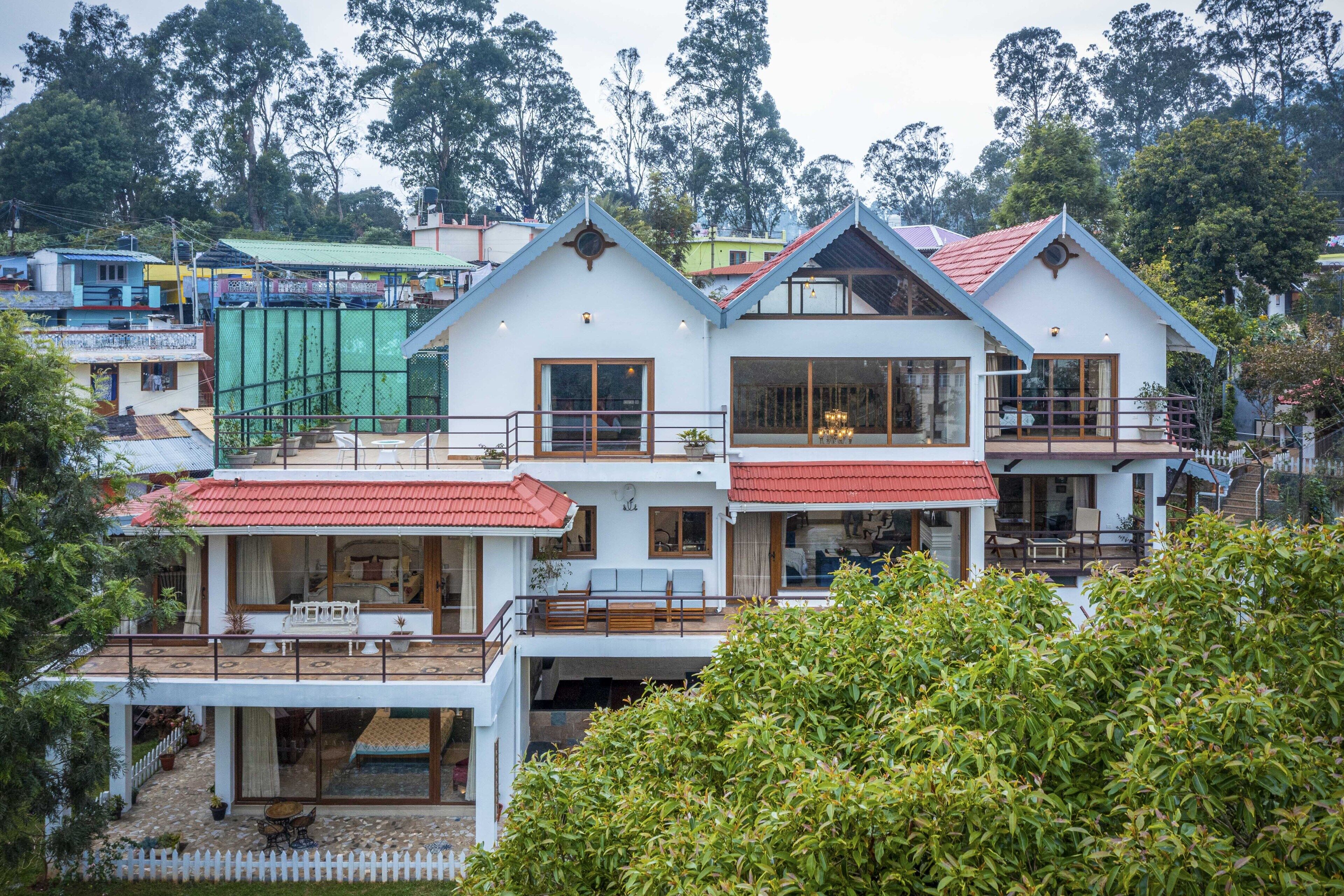 Un edificio residencial de varios pisos con balcones, ventanas grandes y un techo de tejas rojas.