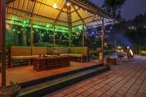 An outdoor patio with a wooden bench, a low table, and a grill. - Amã Stays & Trails Werifesteria, Coonoor (Coonoor)