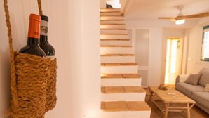 Eine Treppe führt zu einer zweiten Etage, ein Couchtisch aus Holz und ein Sofa befinden sich in einem Wohnbereich.