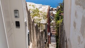 A narrow street with buildings on both sides, a gate, and a view of the sea. - Blue Waves (Positano)