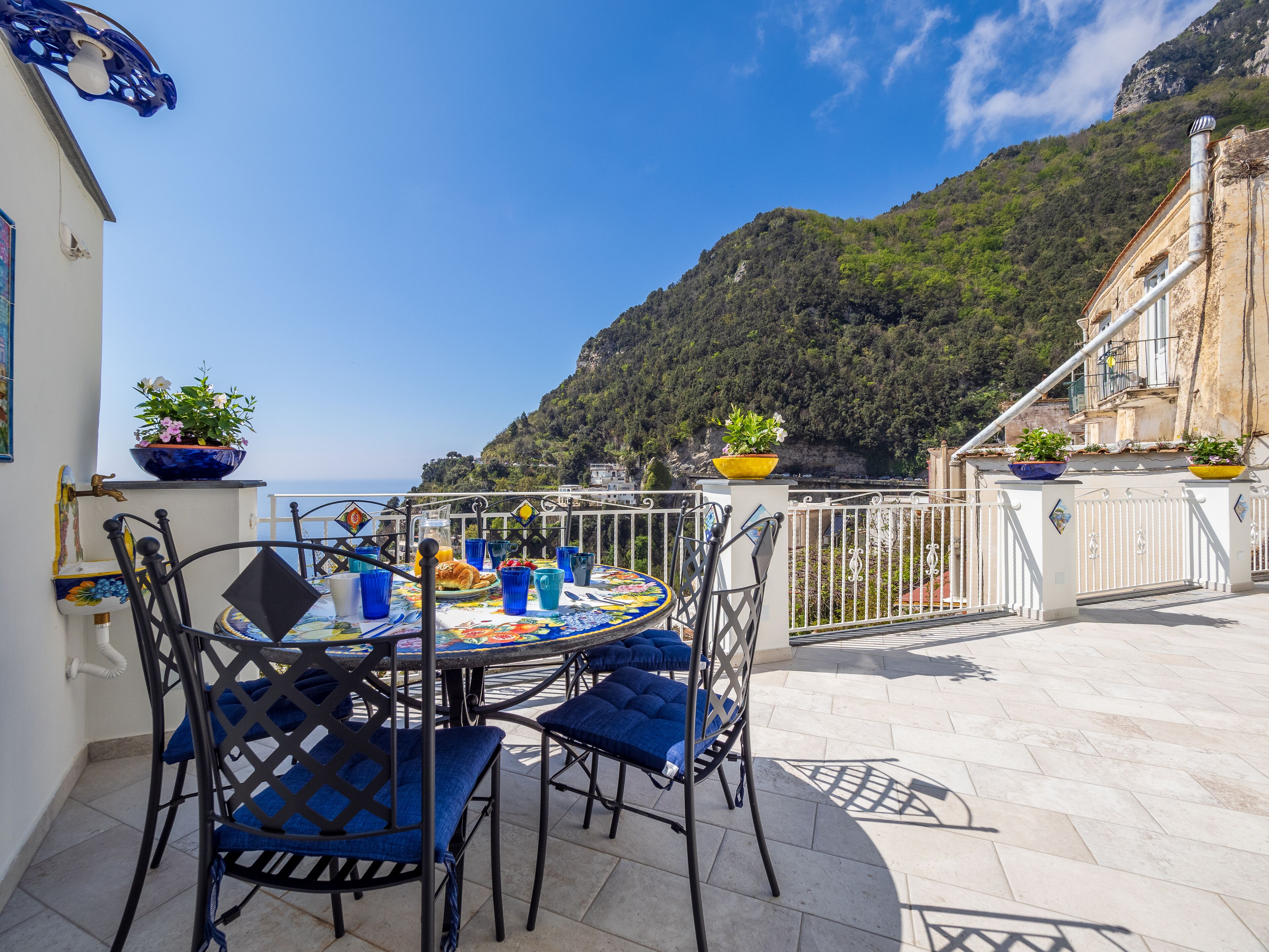 Una terrazza con un tavolo apparecchiato per la colazione, con vista su un paesaggio montuoso.