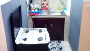 Una cocina pequeña con estufa a gas, pileta y placares.