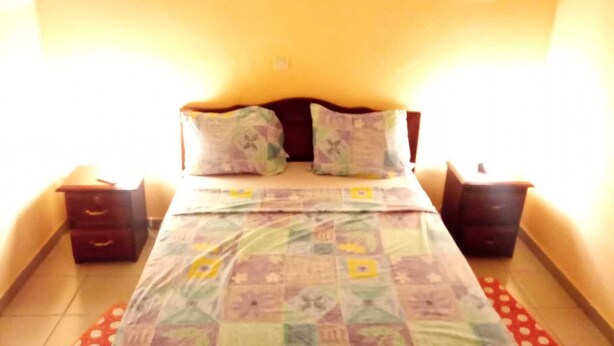 Un dormitorio con cama, dos mesitas de noche y una pared con un cartel que dice 'LOVE'.