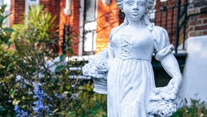 A statue in a garden with a brick building in the background. - Ingledene Guest House  (Bournemouth)