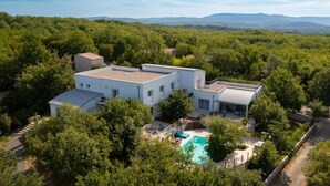 Ein modernes Haus mit Swimmingpool, umgeben von dichtem Baumbestand.