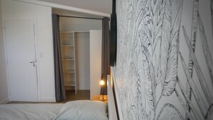 Un dormitorio con una cama, un armario y un televisor montado en la pared.