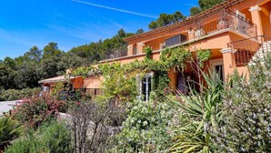 A Mediterranean-style villa with a terracotta facade, a balcony with metal railings, and lush greenery surrounding the property. - Villa Théia (Flayosc)