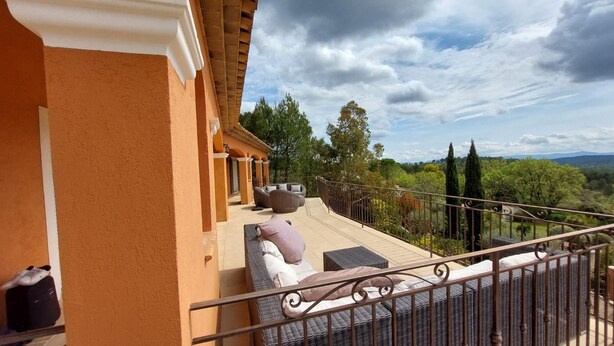A balcony with outdoor seating, a railing, and a view of the surrounding landscape. - Villa Théia (Flayosc)